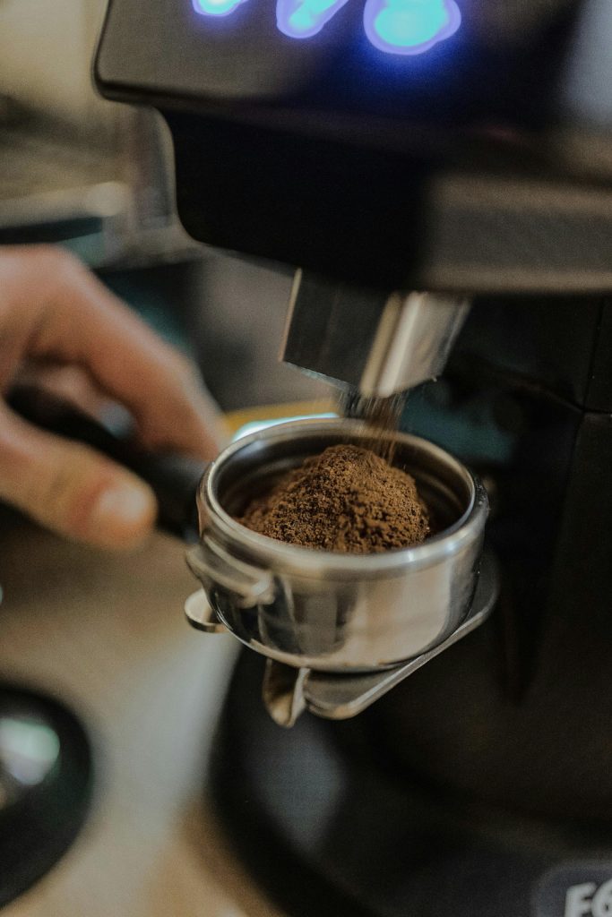 Kaffee wird gemahlen und fällt in einen Siebträger.