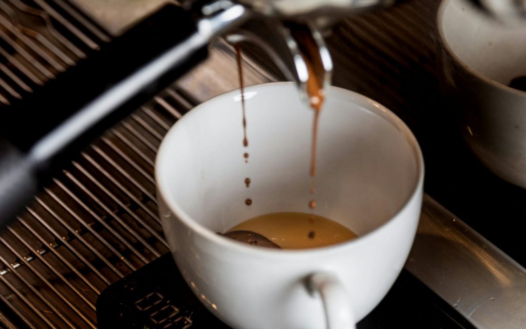 Espresso läuft in eine Espressotasse, die in einer Espressomaschine steht.