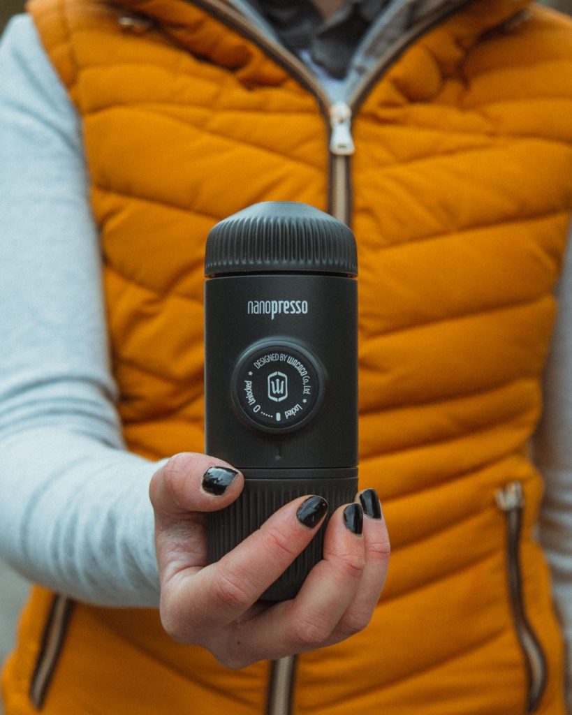Eine Person in outdoor Kleidung hält die AeroPress Alternative Nanopresso mit einer Hand.