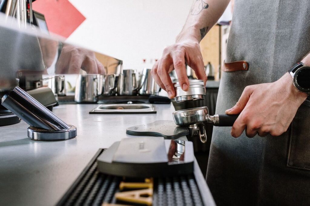 Barista mit Tamper und Siebträger - Kaffeezubereitung